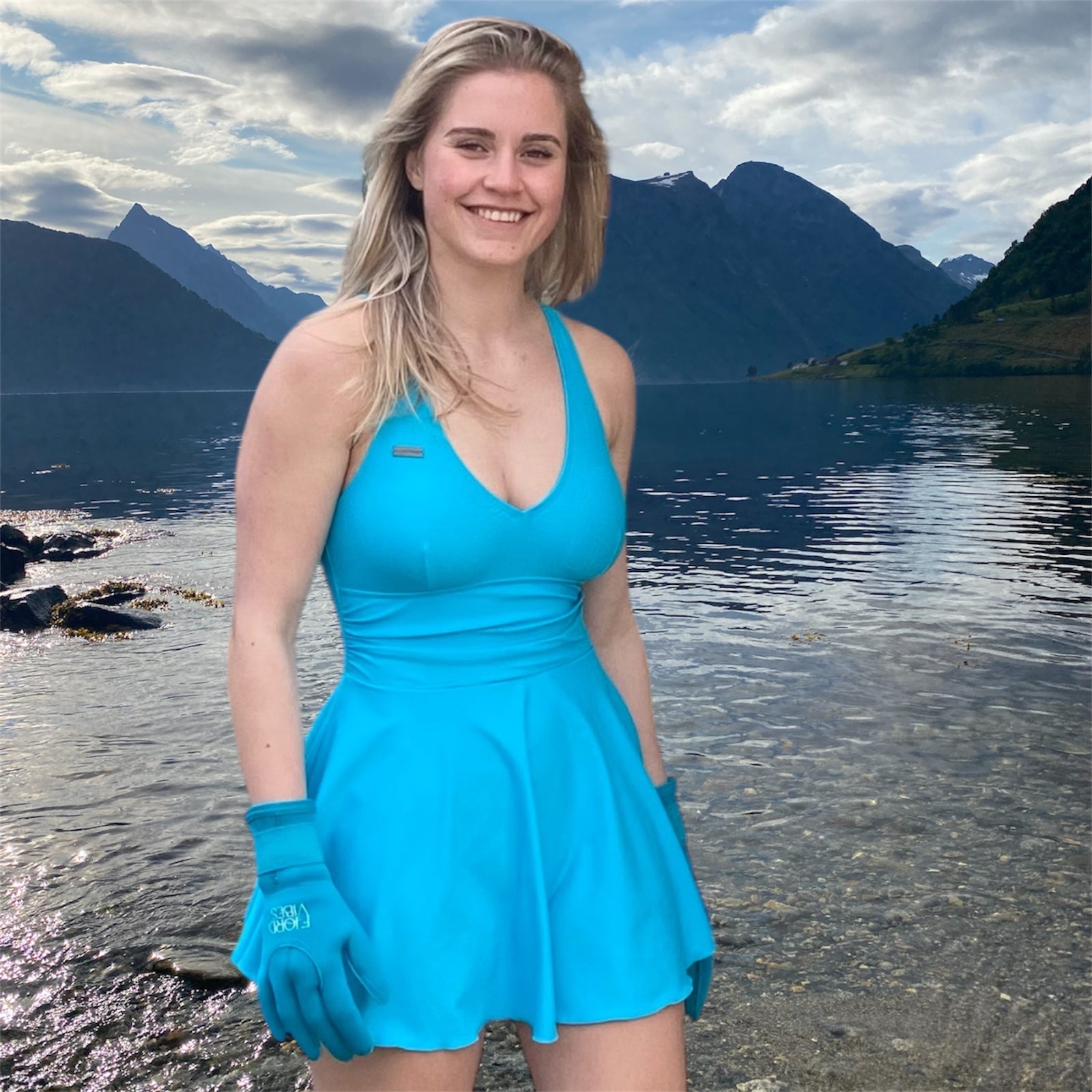 dame som smiler ved en fjord i Norge som har på seg badekjole og neopren hansker